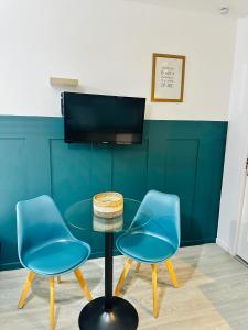 - deux chaises bleues et une table en verre dans une pièce dans l'établissement BtoBed - Studios Paris Le Bourget, au Bourget