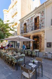 een openluchtrestaurant met tafels en stoelen en een parasol bij LOFT TEATRO ~ Alicante in Alicante