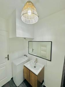 La salle de bains blanche est pourvue d'un lavabo et d'un miroir. dans l'établissement BtoBed - Studios Paris Le Bourget, au Bourget