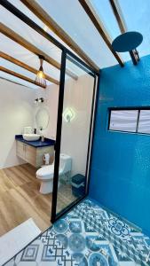 a bathroom with a toilet and a blue wall at Macas Glamping in Macas