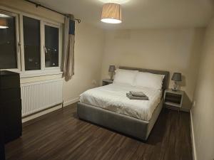 a bedroom with a bed with a night stand and a window at KING ROOMS BY WEMBLEY STADiUM in London