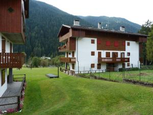 a large white building with red windows and a green field at Via Padova in Auronzo di Cadore