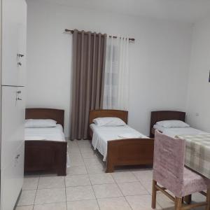 a room with two beds and a table and a chair at Hostel Casa Mia SR in Sarandë