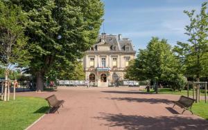 dois bancos num parque em frente a um edifício em Esprit Nogentais - Vue sur Tour Eiffel em Nogent-sur-Marne