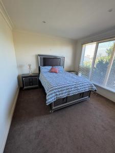 1 dormitorio con 1 cama con edredón azul y 2 ventanas en Luxurious Townhouse Retreat in Prestigious Brighton en Melbourne