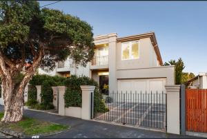 a white house with a gate and a tree at Luxurious Townhouse Retreat in Prestigious Brighton in Melbourne