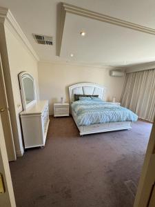 een slaapkamer met een bed, een dressoir en een spiegel bij Luxurious Townhouse Retreat in Prestigious Brighton in Melbourne