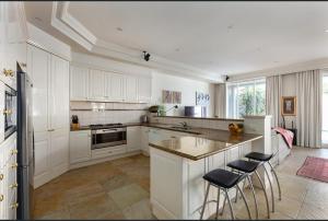 a kitchen with white cabinets and a island with bar stools at Luxurious Townhouse Retreat in Prestigious Brighton in Melbourne