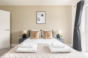 a white bedroom with a large bed with two lamps at Modern 2 Bed Apartment London Lewisham - Perfect for Long Stays in London