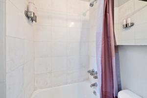 a bathroom with a white tub and a shower at Centrally located Manhattan apartments ,Times Square/Hell’s kitchen in New York