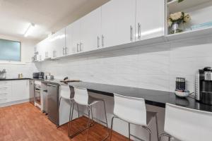 a kitchen with white cabinets and bar stools at MOANA I Walk to Beach & River in Ocean Grove
