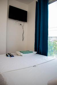Hotel Grand Horizon Rodadero في سانتا مارتا: غرفة نوم مع سرير وتلفزيون على الحائط