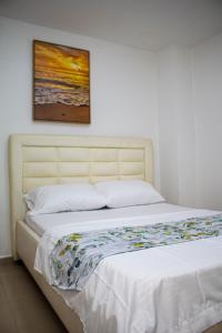 a bed in a bedroom with a painting on the wall at Hotel Grand Horizon Rodadero in Santa Marta