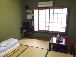 sala de estar con sofá, mesa y ventana en International Inn Kokage, en Beppu