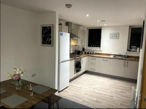 a kitchen with a table and a white refrigerator at Emerald View Luxury 2 Bed Flat with Balconette in Sheffield
