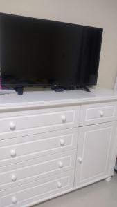 a flat screen tv sitting on top of a white dresser at Alice in Porto Seguro