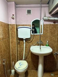 Ein Mann fotografiert ein Bad mit WC und Waschbecken in der Unterkunft Samir Gues Hause in Ganja