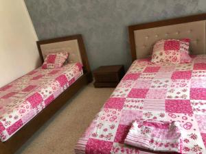 two beds in a bedroom with pink and pink quilt at La villa H in Houmt Souk