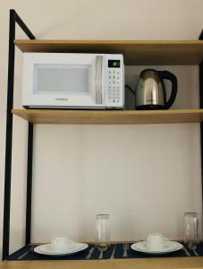 a microwave sitting on a shelf with two plates at Lory Studio Hotel in São Paulo
