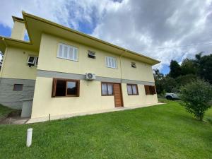 グラマドにあるResidencial Encantos da Naturezaの前に緑の芝生が広がる黄色い家