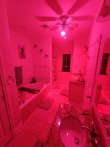 a pink bathroom with a toilet and a tub and a sink at Home lux in Louisiana in Laplace