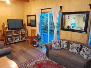 a living room with a couch and a large window at Cabaña Cacique Vista Hermosa in Cochamó