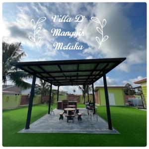 een paviljoen met een tafel en stoelen in een tuin bij Villa D' Manggis Melaka in Melaka