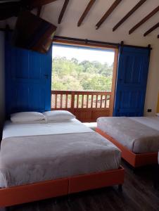 two beds in a room with a large window at Casa Iris Hotel Boutique in Barichara