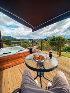 a table with a plate of food on a deck with a hot tub at Glamping Carmen de Viboral in Carmen de Viboral
