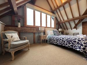 Schlafzimmer mit einem Bett, einem Stuhl und Fenstern in der Unterkunft Beautiful country barn with hot tub and amazing views in Princes Risborough