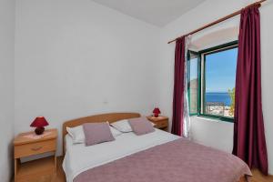 a bedroom with a bed and a large window at Apartments by the sea Igrane, Makarska - 20373 in Igrane