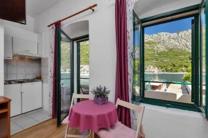 a small table with a pink table cloth on it in a room with a window at Apartments by the sea Igrane, Makarska - 20373 in Igrane