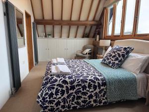 ein Schlafzimmer mit einem Bett mit einer blauen und weißen Decke in der Unterkunft Beautiful country barn with hot tub and amazing views in Princes Risborough