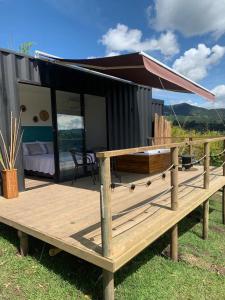 a small house with a deck with a bed at Glamping Carmen de Viboral in Carmen de Viboral
