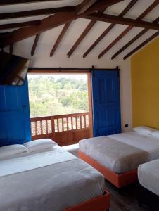 two beds in a room with blue doors and a window at Casa Iris Hotel Boutique in Barichara