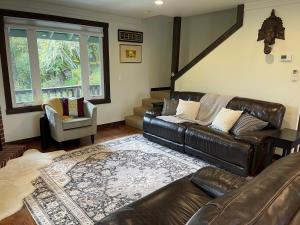 sala de estar con sofá de cuero y silla en Avenue of the Giants River View Home (#1), 