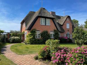 a large brick house with a thatched roof at Ferienhaus Friesenrose in Nieblum