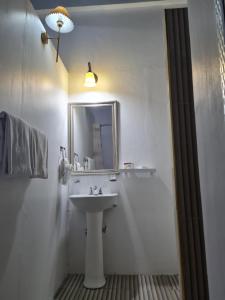 Baño blanco con lavabo y espejo en Sky Beach Rooms, en Lucea