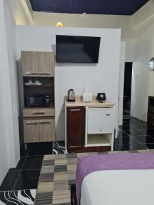 a room with a bed and a kitchen with a tv at Sky Beach Rooms in Lucea
