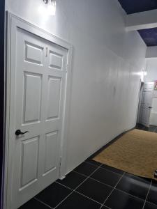 a white door in a room with a tiled floor at Sky Beach Rooms in Lucea