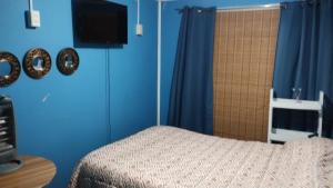 a bedroom with blue walls and a bed and a television at QUELKUN, FAMILIAR in Quellón