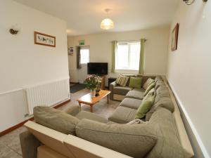 a living room with a large couch and a tv at Stags Cottage in North Molton