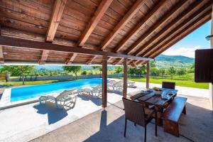 an outdoor patio with a table and chairs and a swimming pool at Family friendly house with a swimming pool Rudopolje Bruvanjsko, Zagora - 21427 in Gračac