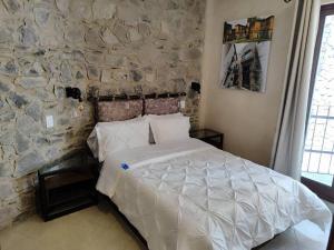 una camera con un letto bianco su un muro di pietra di Loft AMORE en Val'Quirico a Santeagueda