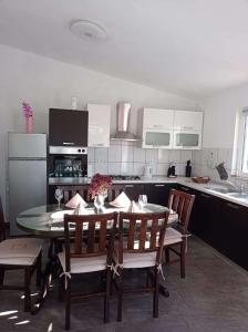 uma cozinha com mesa e cadeiras e uma cozinha com armários brancos em Apartments with a parking space Slime, Omis - 22826 em Omiš
