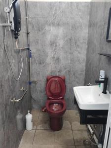 uma casa de banho com um WC vermelho e um lavatório. em Padang Serai Cozy Roomstay Share Bathroom em Padang Serai