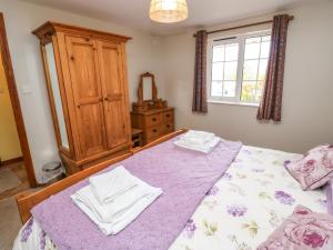 um quarto com uma cama com lençóis roxos e uma janela em Otters Holt em North Molton