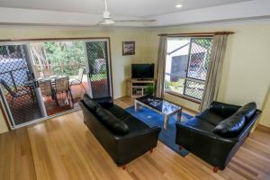 a living room with two black leather couches and a table at McLeods - Pet-friendly beach house in Agnes Water in Agnes Water