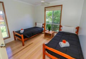 two beds in a room with two windows at McLeods - pet-friendly beach house in Agnes Water in Agnes Water