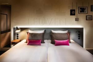 - un grand lit blanc avec deux oreillers roses dans l'établissement pentahotel Leuven, à Louvain